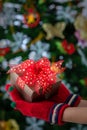 Hands in colorful red gloves holding give box with beautiful bow