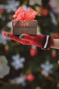 Hands in colorful red gloves holding give box with beautiful bow