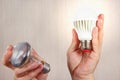Hands compared incandescent bulb and glowing ecofriendly led lamp Royalty Free Stock Photo