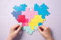 Hands connect heart-shaped puzzle pieces against a blue backdrop. Royalty Free Stock Photo