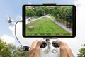 Hands controlling drone filming park against cloudy sky