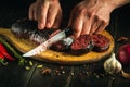 The hands of the cook cut the blood sausage with a knife. Cooking a national dish on the kitchen table with fragrant rosemary and Royalty Free Stock Photo