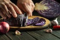 Hands of the cook cut red cabbage with a knife on a kitchen cutting board. Cooking vegetarian food at home Royalty Free Stock Photo