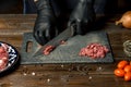 Hands of the cook in gloves cut the red meat on the board. nearby are tomatoes, onion, butter Royalty Free Stock Photo