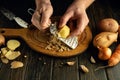 The hands of a cook with a grater grate raw potatoes on the kitchen table. Concept of preparing delicious vegetable breakfast Royalty Free Stock Photo