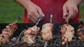 Shish kebab grilling on skewers outdoors. Hands cooking barbecue kebab.