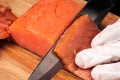 Hands cooks close-up. The chef cuts with a knife a red fish, smoked salmon on a wooden cutting board. Royalty Free Stock Photo