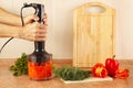 Hands cooks mixed red pepper and tomato in blender Royalty Free Stock Photo