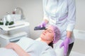 Hands of cosmetologist making ultrasound facial cleaning with special machine Royalty Free Stock Photo