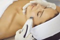 Hands of cosmetologist making ultrasound facial cleaning with special machine for relaxing woman Royalty Free Stock Photo