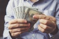 hands counting dollar banknotes on dark wooden surface