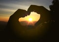 Hands of couple lover forming a heart shape with sunset silhouette background Royalty Free Stock Photo