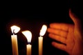 Hands covering the candle light in dark designs for the background, candles in the dark, white wax candles are burning with consis Royalty Free Stock Photo