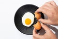 Hands cracking Fried egg on black plate on white background. Cooking and food concept