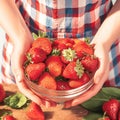 Hands cradle a bowl of luscious strawberries, a tempting summer treat