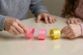 Hands crafting colorful paper chains garland on white table Royalty Free Stock Photo