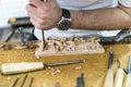 Hands of the craftsman carve a bas-relief with a gouge