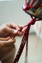 Hands of a craftsman knitting handmade macrame.