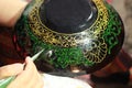 hands of a craftswoman painting decorative lacquer on traditional plates and bowls at a craft night market stall in Northern