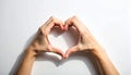 Hands creating a heart shape on a white surface with a distinct shadow love gesture Royalty Free Stock Photo