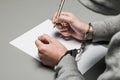 Hands of the criminal in handcuffs write a handle on paper. Sincere confession, request, statement. Justice