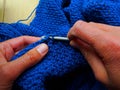 Hands that are crocheting with blue wool