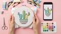 Hands Cross-Stitching Cactus Design with Digital Pattern on Pink Background Royalty Free Stock Photo