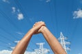 Hands crossed in assent and power transmission lines against blu Royalty Free Stock Photo