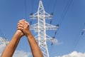 Hands crossed in assent and power transmission lines against blu Royalty Free Stock Photo