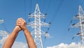 Hands crossed in assent and power transmission lines against blu Royalty Free Stock Photo