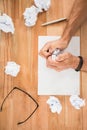 Hands crumpling paper on wooden desk