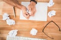 Hands crumpling paper on wooden desk