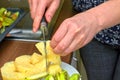 Hands cut a pineapple into a white plate with a knife Royalty Free Stock Photo