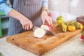 Hands cutting an apple on chopping board. Young woman preparing a fruit salad in her kitchen Royalty Free Stock Photo