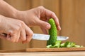 Hands cutting cucumber for salad on the wooden chopping board Royalty Free Stock Photo