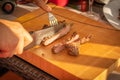 Hands cutting just grilled meat on a hand craft wooden board