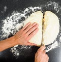 Hands cutting a lump of dough with knife