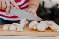 Hands cutting mushrooms with a knife on a wooden board