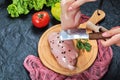 Hands cutting piece of raw chicken fillet on wooden plate with fresh vegetables and tablecloth Royalty Free Stock Photo