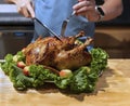 Hands cutting roast capon turkey,chicken on the kitchen table