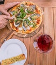 Hands cutting a seafood pizza with New Zealand NZ green lipped m Royalty Free Stock Photo