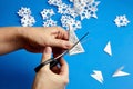 Hands cutting paper snowflakes over blue background Royalty Free Stock Photo