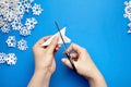 Hands cutting paper snowflakes over blue background Royalty Free Stock Photo