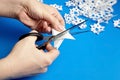 Hands cutting paper snowflakes over blue background Royalty Free Stock Photo