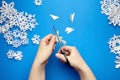 Hands cutting paper snowflakes over blue background Royalty Free Stock Photo