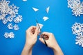 Hands cutting paper snowflakes over blue background Royalty Free Stock Photo