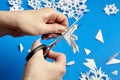 Hands cutting paper snowflakes over blue background Royalty Free Stock Photo