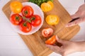 Hands cutting yellow tomato near a white plate with fersh red tomatoes Royalty Free Stock Photo