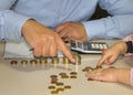 Hands of a dad and daughter teaching how to count money. Row of pennies and calculator on the table Royalty Free Stock Photo