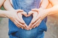 Hands of , dad and mom lie in the form of a heart on a pregnant belly Royalty Free Stock Photo